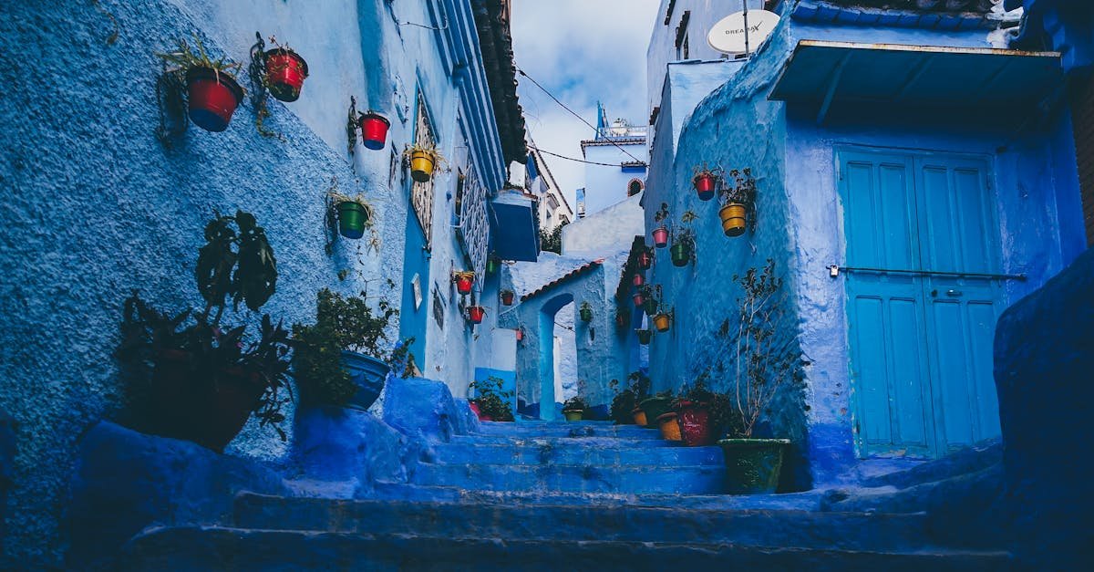 Colorful pots line the blue-washed walls of a narrow alley in Chefchaouen, Morocco.