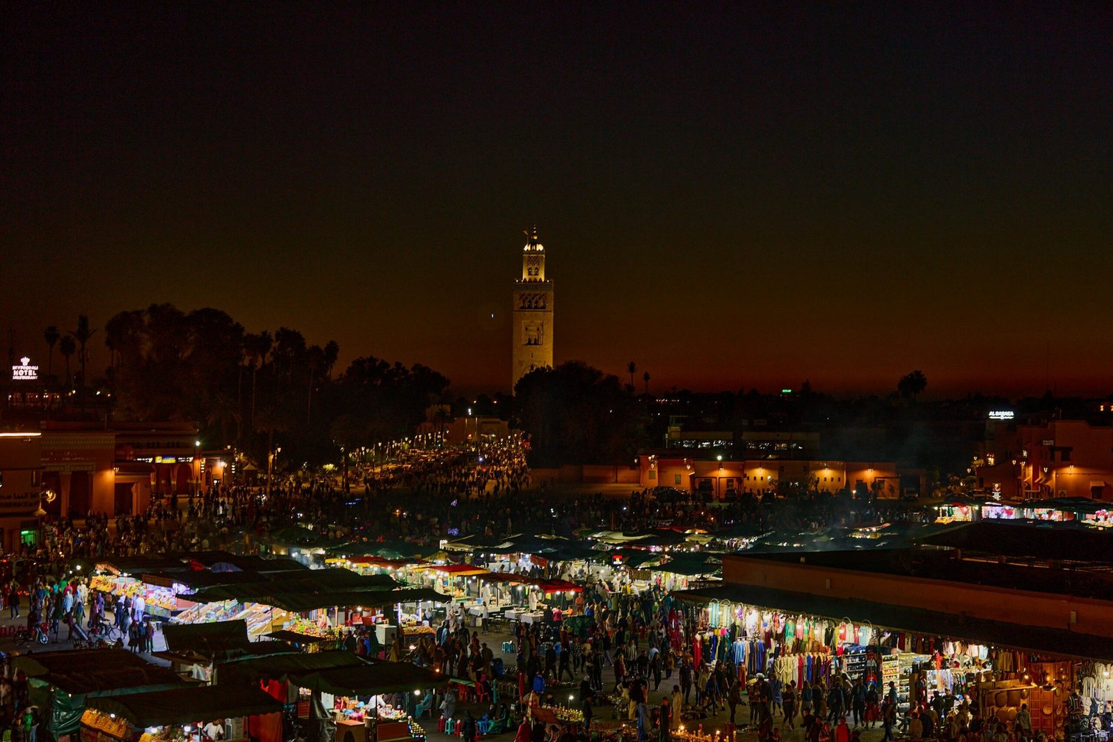 Experience the bustling night market in Marrakesh, Morocco, illuminated against a stunning twilight sky.