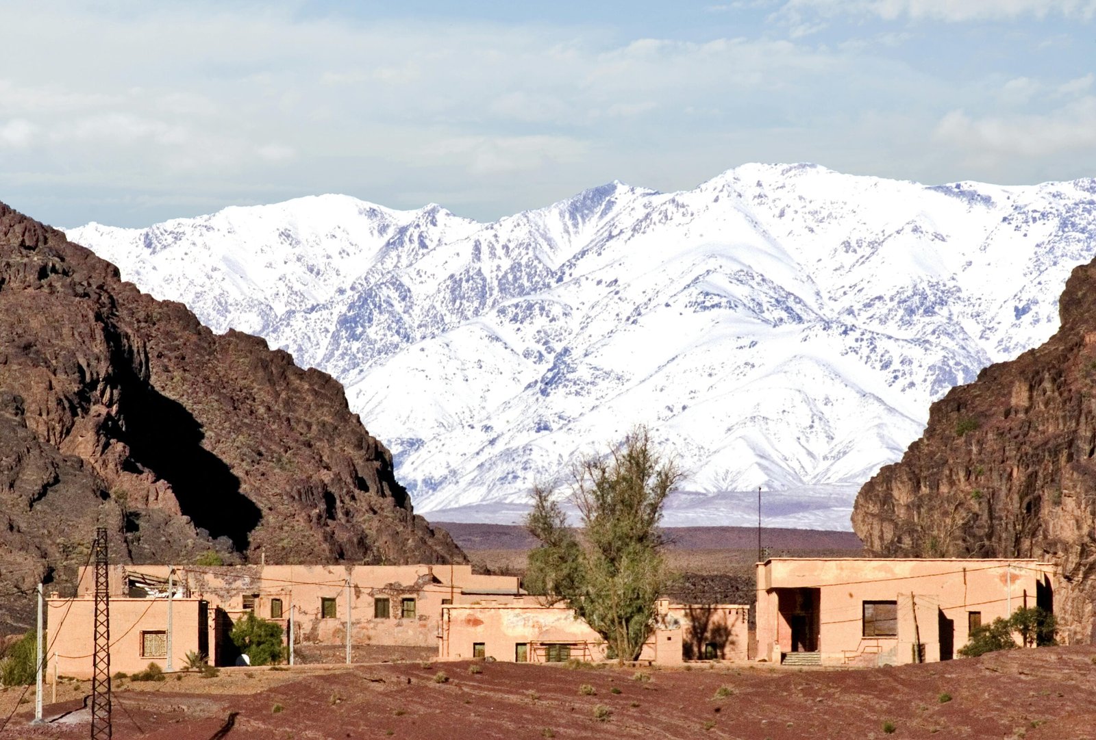 Village in Ouarzazate with snowy Atlas Mountains in the background.